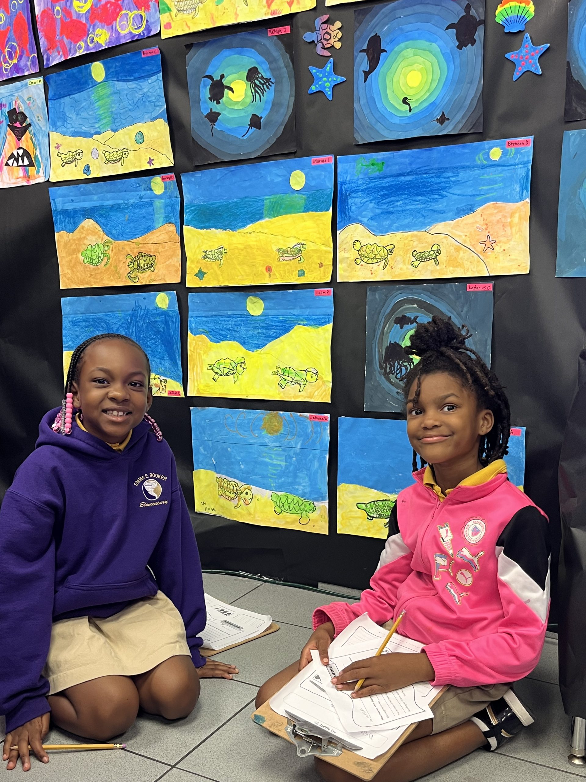 Two students sitting near fluorescent artwork